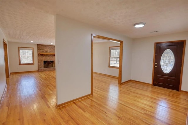 foyer entrance featuring light wood-type flooring and a fireplace