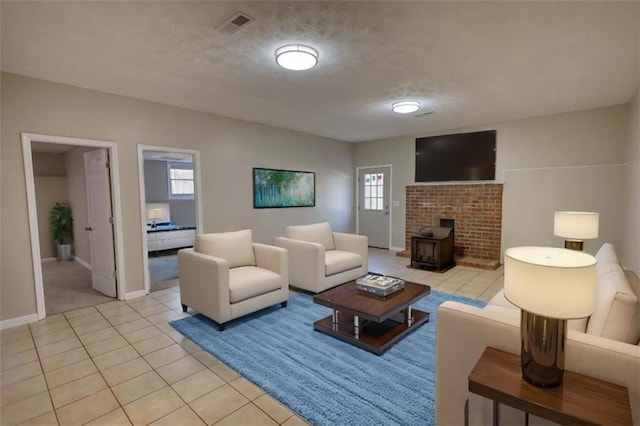 living room with a wood stove, a textured ceiling, and light tile patterned flooring