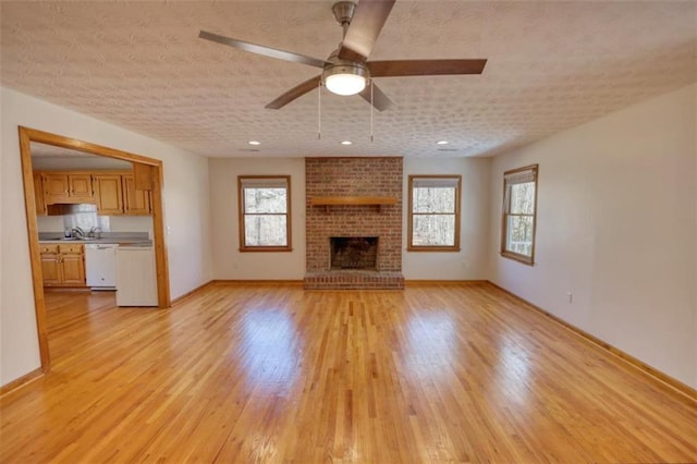 unfurnished living room featuring a brick fireplace, light hardwood / wood-style flooring, and ceiling fan