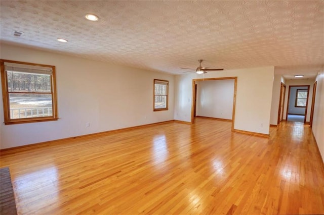 empty room with a textured ceiling, ceiling fan, and light hardwood / wood-style floors