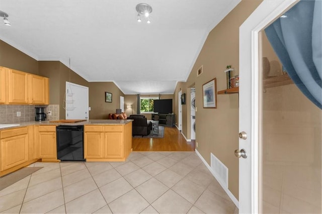 1822 N Rock Springs Rd NE Unit 24, Atlanta, GA 30324 - kitchen featuring dishwasher, stacked washing machine and dryer, light brown cabinetry, vaulted ceiling, and light countertops