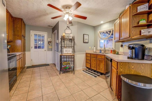 kitchen featuring sink, stainless steel dishwasher, light tile patterned floors, ceiling fan, and black / electric stove