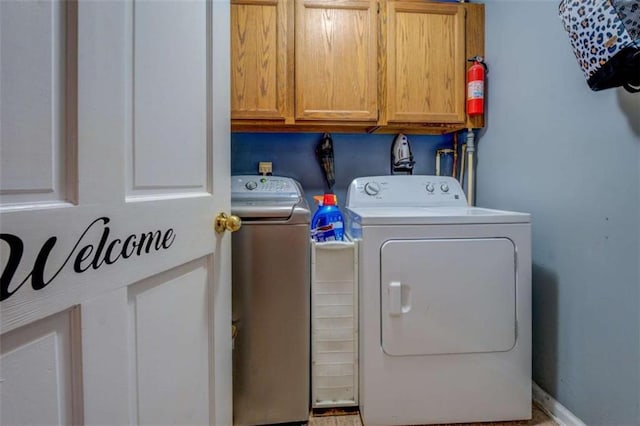 clothes washing area with cabinets and independent washer and dryer