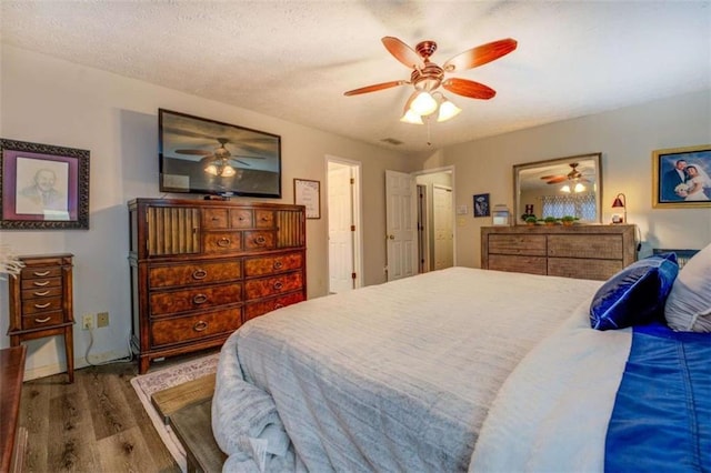 bedroom featuring ceiling fan, a textured ceiling, and dark hardwood / wood-style flooring