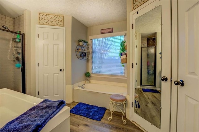 bathroom with hardwood / wood-style flooring, independent shower and bath, and a textured ceiling