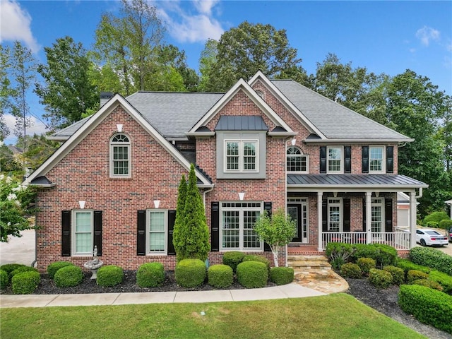 view of front facade with a standing seam roof, a porch, roof with shingles, and metal roof