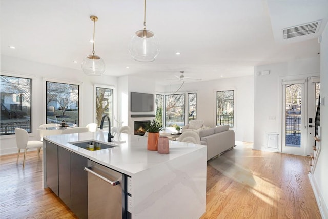 kitchen with sink, decorative light fixtures, dishwasher, ceiling fan, and light hardwood / wood-style floors