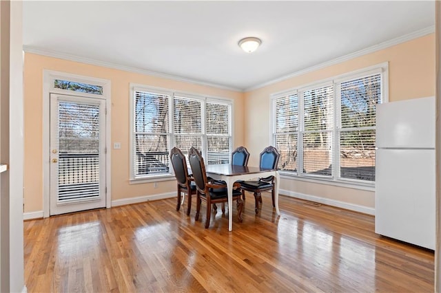 dining room with light wood-type flooring and ornamental molding