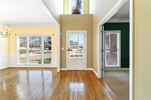 foyer entrance with wood-type flooring, crown molding, and an inviting chandelier