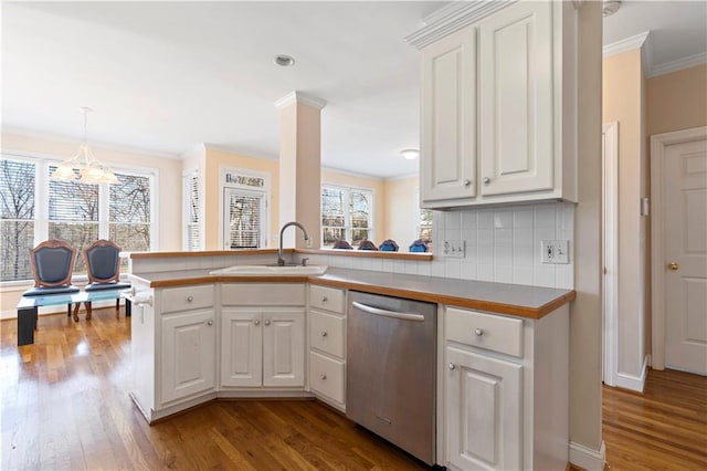 kitchen featuring kitchen peninsula, stainless steel dishwasher, sink, an inviting chandelier, and white cabinetry