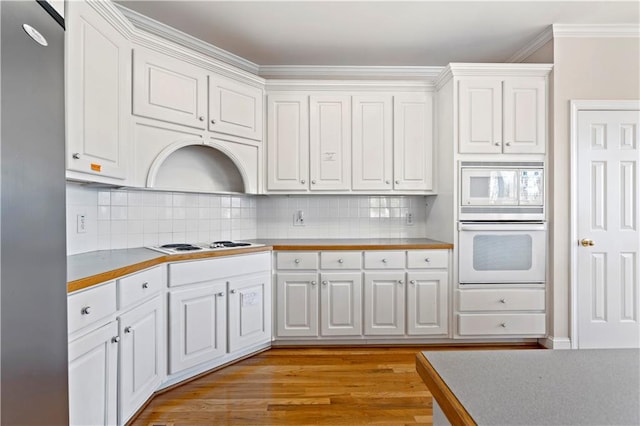 kitchen with white appliances, decorative backsplash, ornamental molding, light hardwood / wood-style floors, and white cabinetry