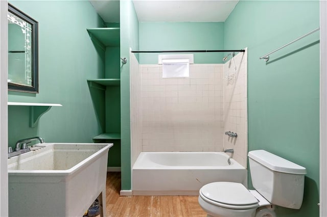 full bathroom featuring tiled shower / bath combo, hardwood / wood-style flooring, toilet, and sink