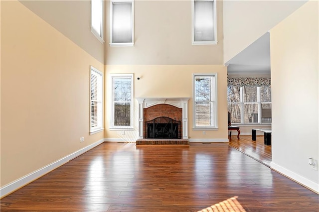 unfurnished living room featuring wood-type flooring and a brick fireplace