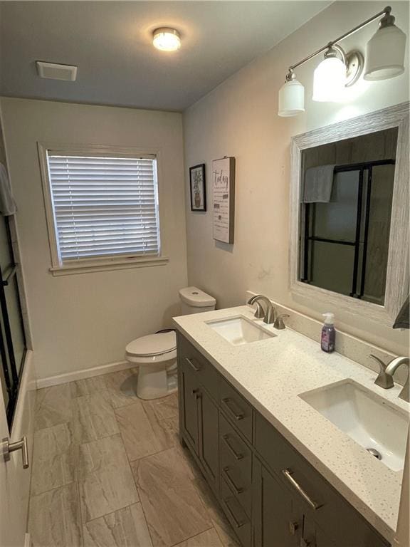 full bathroom with double vanity, baseboards, toilet, and a sink