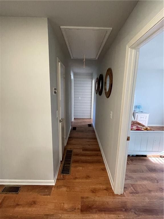 corridor featuring attic access, visible vents, dark wood finished floors, and baseboards