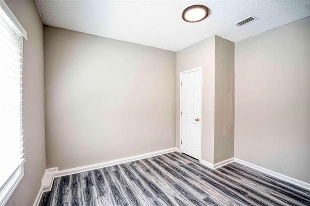 spare room with a textured ceiling and dark wood-type flooring