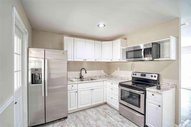 kitchen with light hardwood / wood-style floors, white cabinetry, sink, and appliances with stainless steel finishes