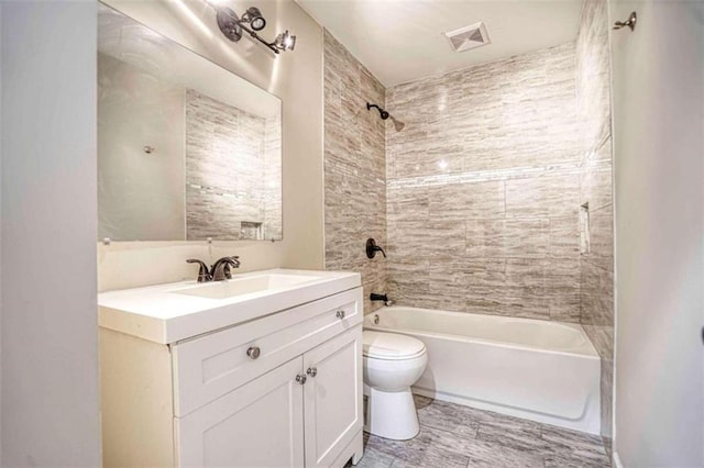 full bathroom featuring vanity, tiled shower / bath combo, and toilet