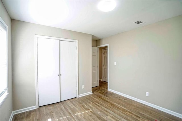 unfurnished bedroom with multiple windows, a closet, and light hardwood / wood-style flooring