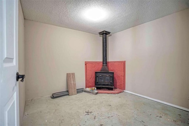 unfurnished living room featuring a textured ceiling, a wood stove, and concrete floors