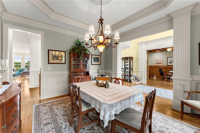 4645 Manor Dr, Gainesville, GA 30506 - dining area with ornate columns, a chandelier, a wainscoted wall, ornamental molding, and light wood-style flooring
