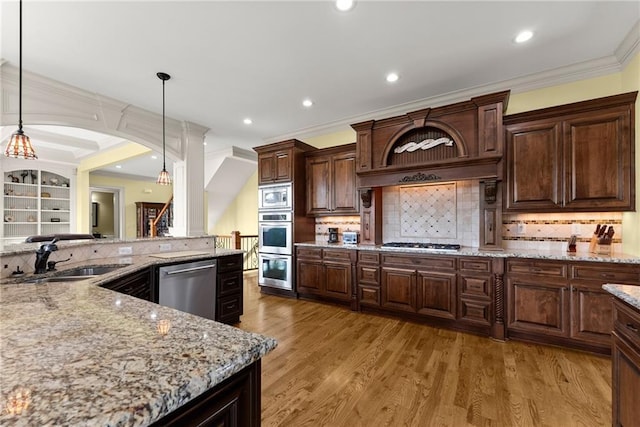4645 Manor Dr, Gainesville, GA 30506 - kitchen featuring appliances with stainless steel finishes, a sink, arched walkways, crown molding, and light wood finished floors