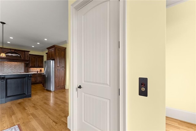 4645 Manor Dr, Gainesville, GA 30506 - kitchen with freestanding refrigerator, light wood-style flooring, ornamental molding, dark brown cabinetry, and light countertops