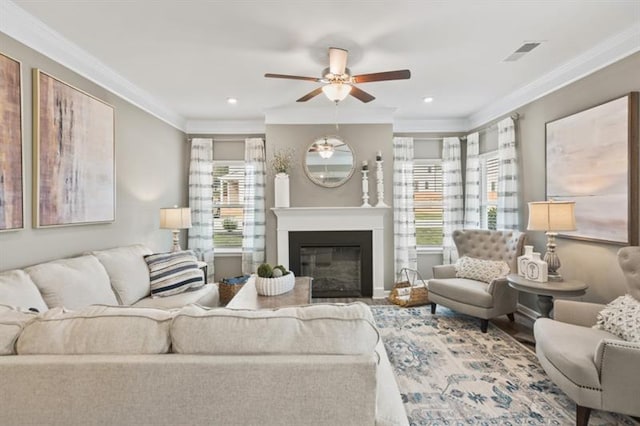 living room featuring a ceiling fan, crown molding, a glass covered fireplace, recessed lighting, and wood finished floors