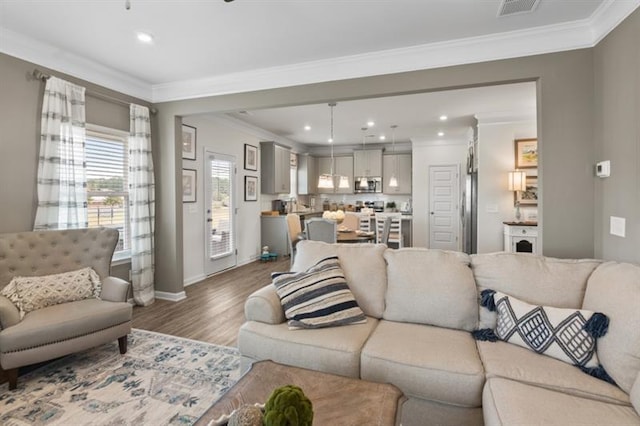 living room featuring wood finished floors, ornamental molding, recessed lighting, and baseboards