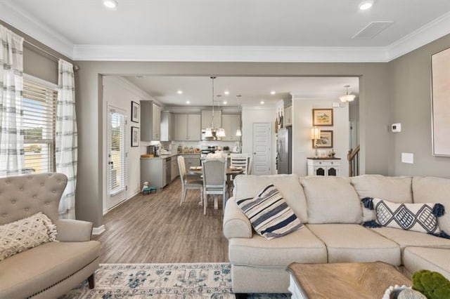 living room with wood finished floors, crown molding, and recessed lighting