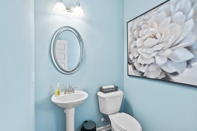 half bath featuring toilet and a sink