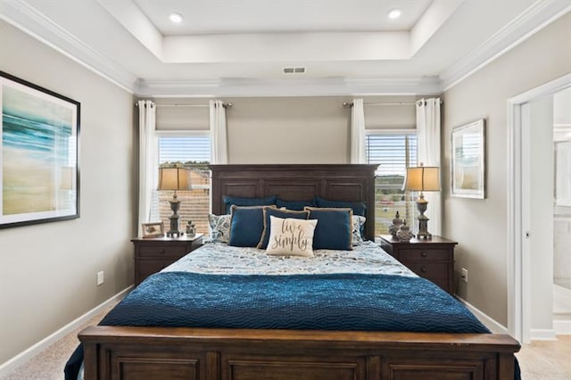 carpeted bedroom with a tray ceiling, multiple windows, baseboards, and ensuite bathroom