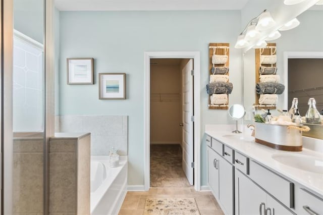 full bath featuring a bath, double vanity, a spacious closet, and tile patterned floors