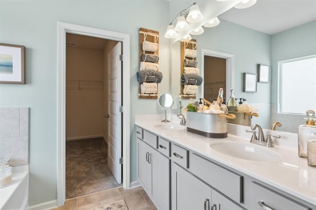 bathroom with a spacious closet, double vanity, and a tub