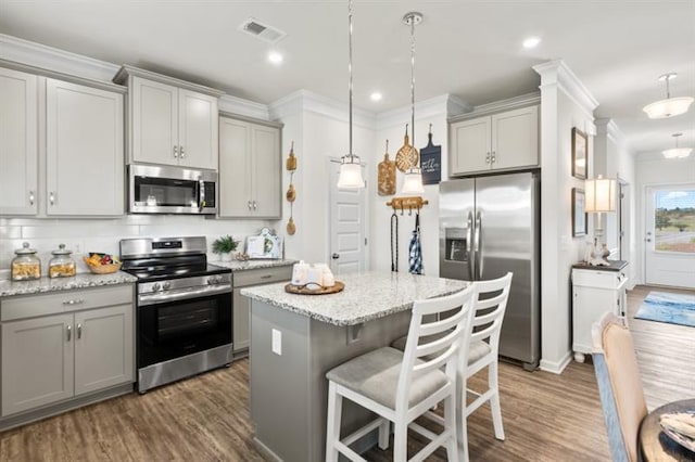 kitchen with appliances with stainless steel finishes, gray cabinetry, dark wood-type flooring, crown molding, and recessed lighting