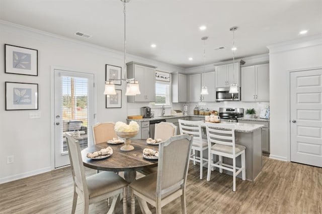 dining space with ornamental molding, wood finished floors, baseboards, and recessed lighting