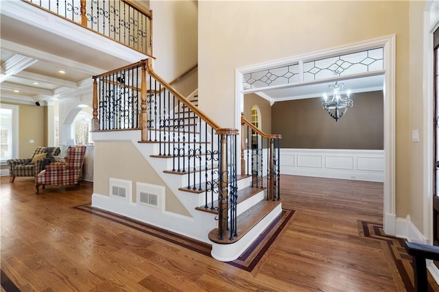 stairway featuring visible vents, beamed ceiling, crown molding, and wood finished floors