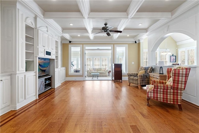 sitting room featuring coffered ceiling, arched walkways, crown molding, beamed ceiling, and light wood-type flooring