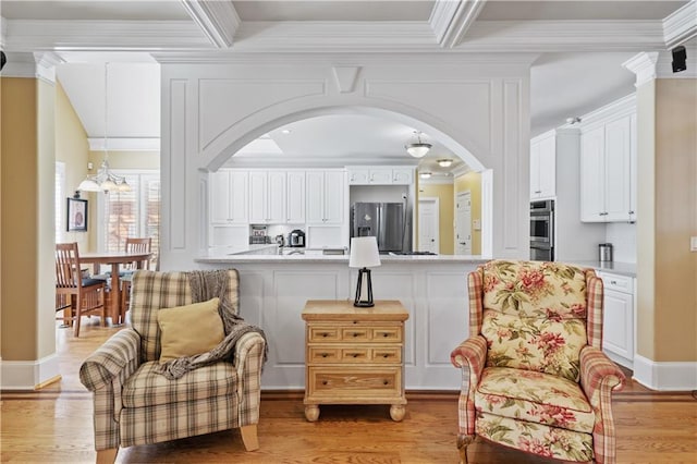 living area featuring a notable chandelier, arched walkways, light wood-type flooring, and ornamental molding