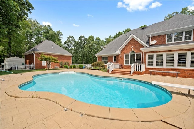 view of swimming pool featuring a patio area, a diving board, a fenced in pool, and fence