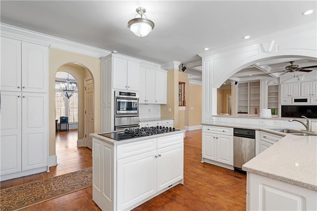 kitchen featuring ceiling fan with notable chandelier, wood finished floors, arched walkways, white cabinetry, and a sink