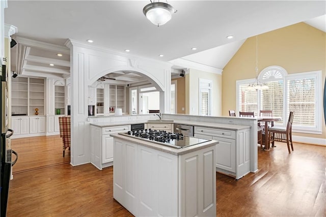 kitchen featuring wood finished floors, a kitchen island, a sink, light countertops, and a chandelier