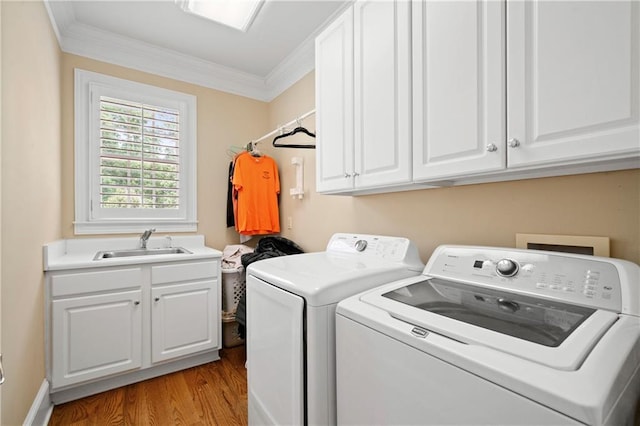 washroom featuring a sink, wood finished floors, cabinet space, crown molding, and washing machine and clothes dryer