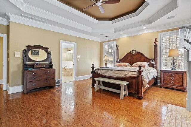 bedroom with hardwood / wood-style floors, a raised ceiling, visible vents, and ornamental molding