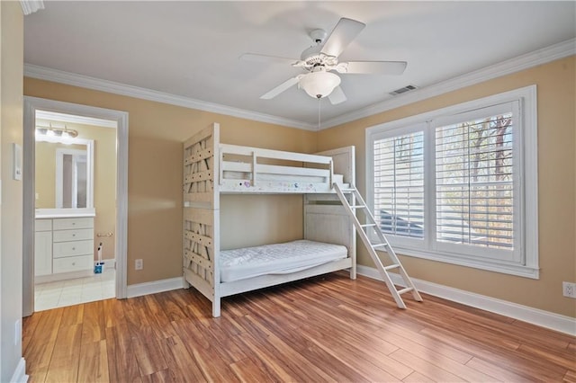 unfurnished bedroom featuring a ceiling fan, baseboards, wood finished floors, visible vents, and ornamental molding