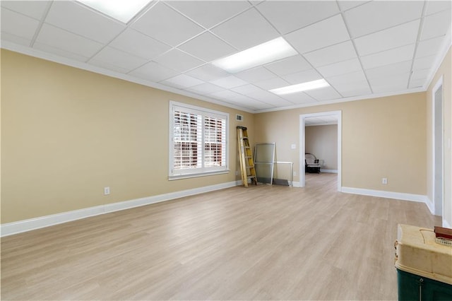 empty room with light wood finished floors, visible vents, a paneled ceiling, and baseboards