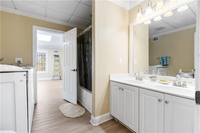 bathroom featuring a sink, visible vents, wood finished floors, and double vanity