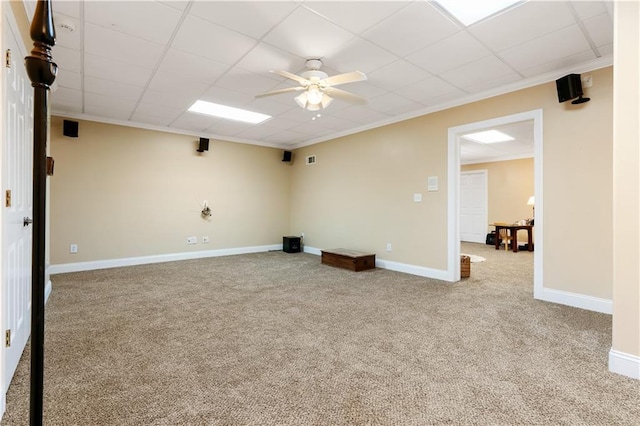 carpeted spare room featuring a drop ceiling, crown molding, and baseboards