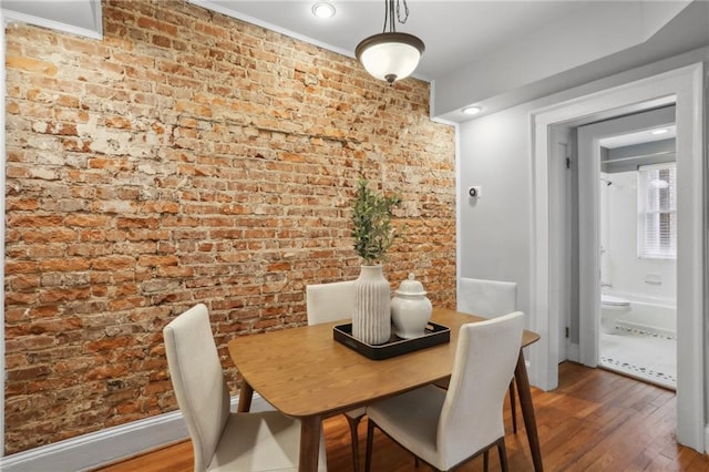 dining room with wood-type flooring and brick wall