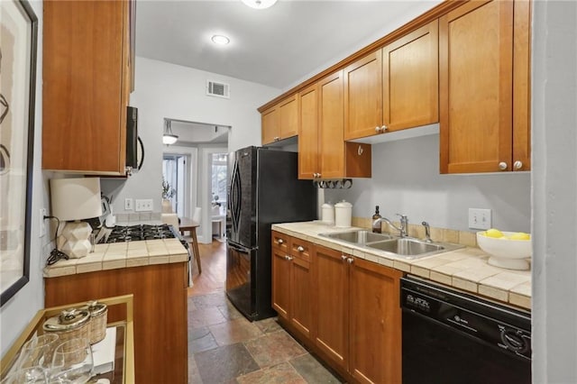 kitchen with sink, tile counters, and black appliances